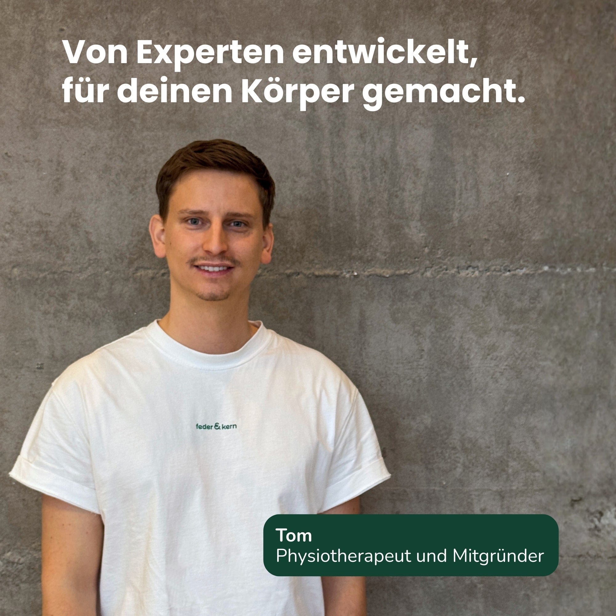 Feder & Kern Physiotherapeut vor grauer Wand, Expertenstatement, weißes T-Shirt mit Logo