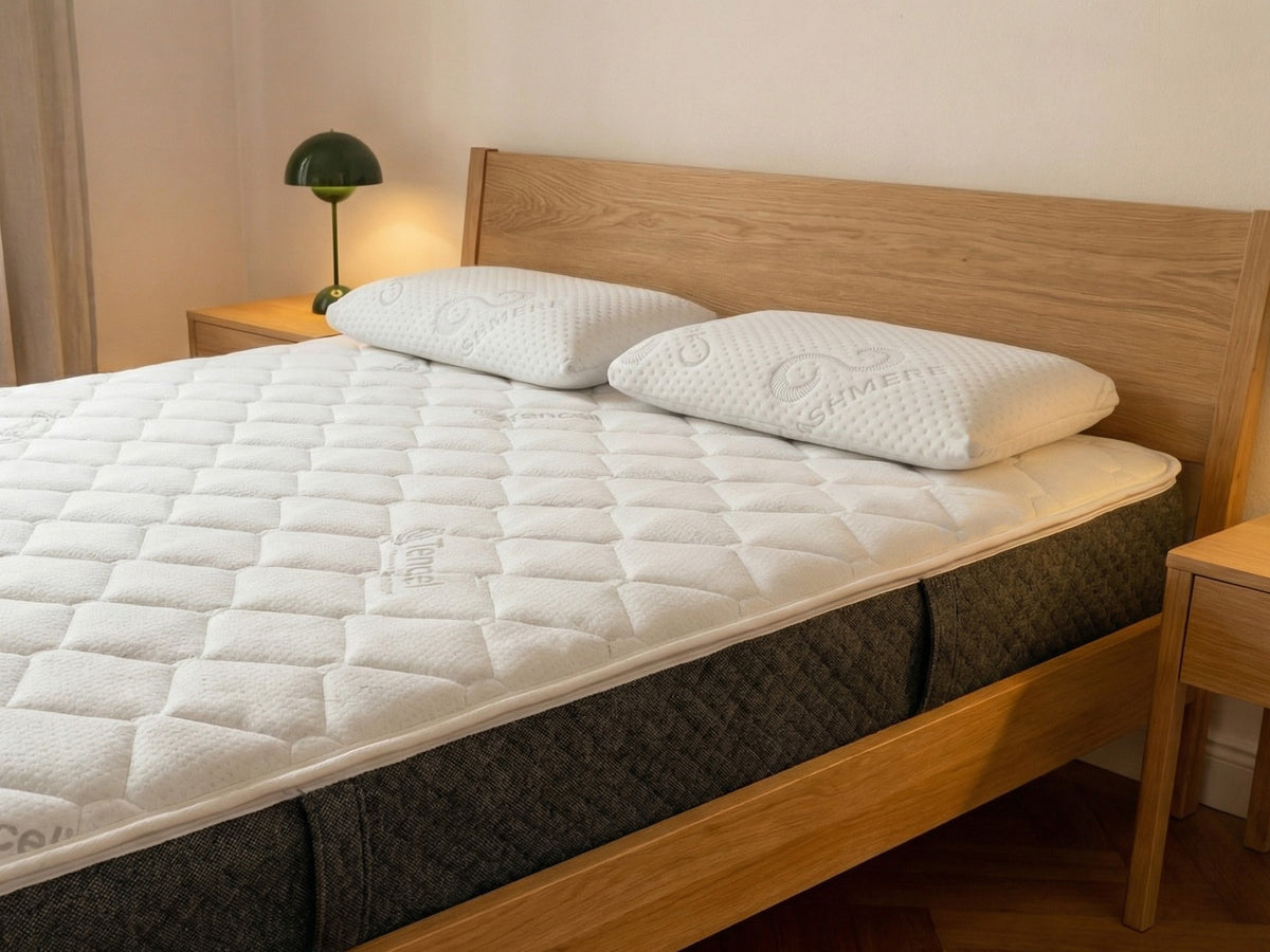 Holzbett mit Feder & Kern Matratze und zwei ergonomischen feder & kern relax Nackenstützkissen in einem schlicht eingerichteten Schlafzimmer.