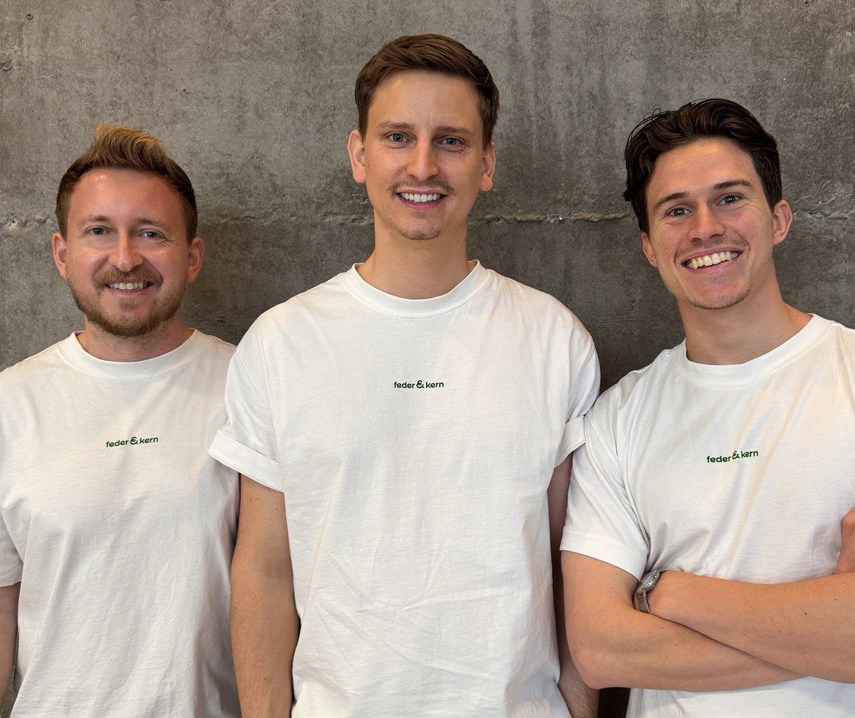 Feder & Kern Teamfoto, drei Männer im weißen Feder & Kern Shirt vor Betonwand, Peter, Tom, Cedric