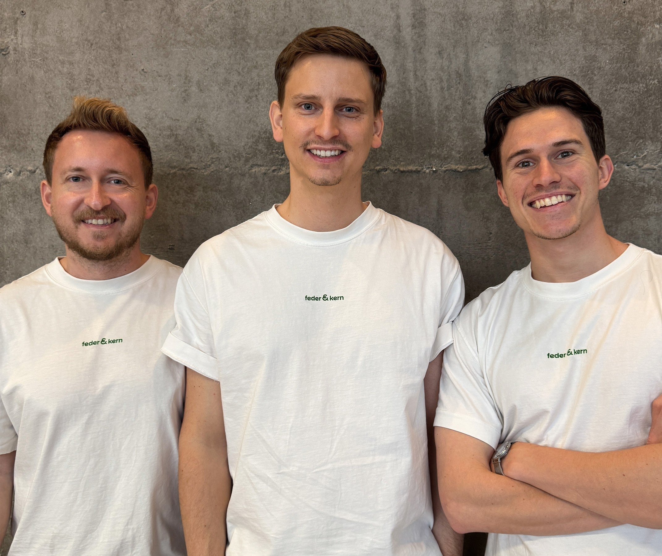 Feder & Kern Teamfoto, drei Männer im weißen Feder & Kern Shirt vor Betonwand, Peter, Tom, Cedric